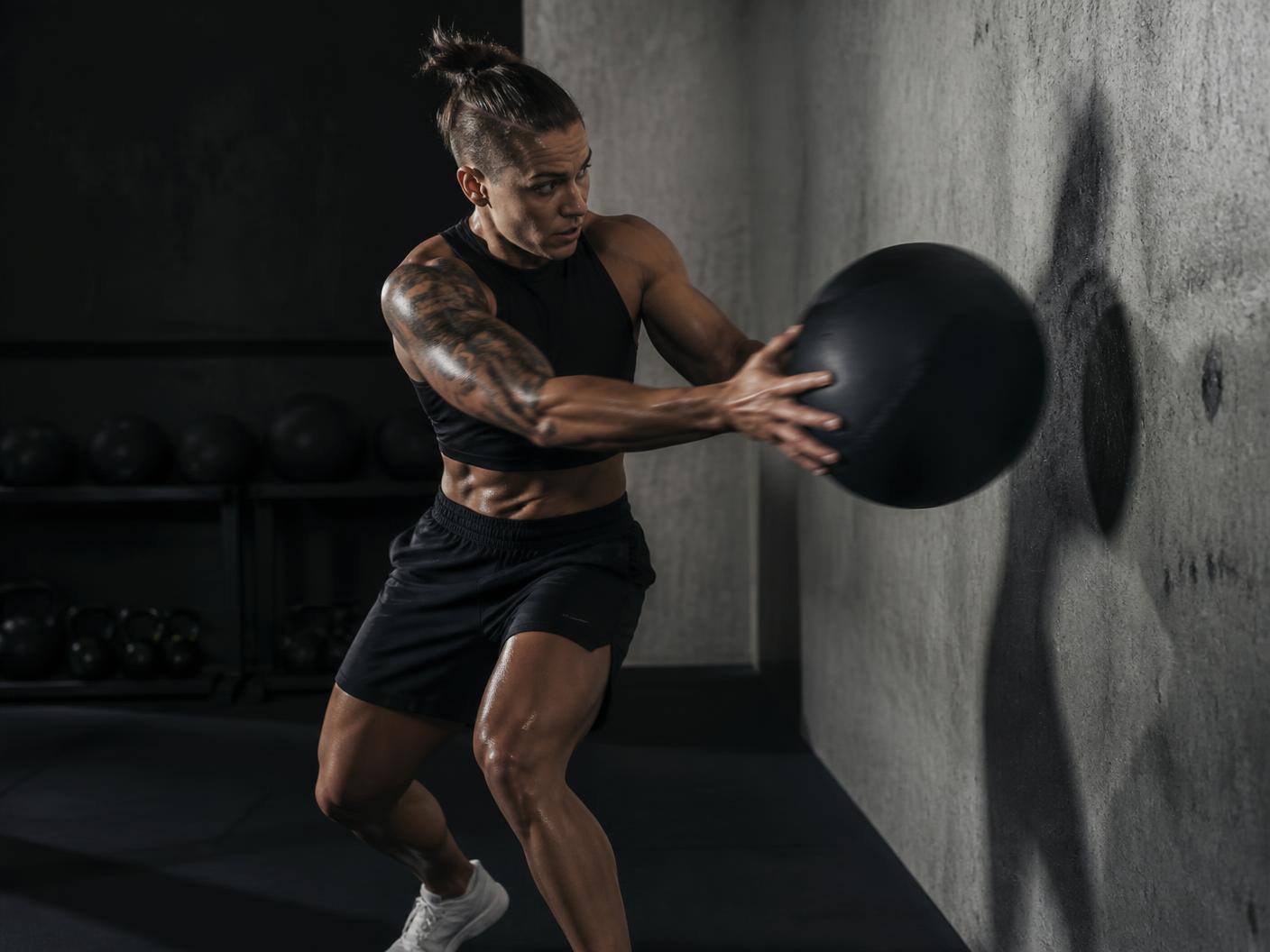 Athlete performing an explosive rotational medicine-ball throw in a dark gym